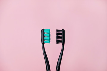 Two black toothbrushes on pink. Relationship between man and woman, Valentines Day and love concept. Backdrop with copyspace. Stock photo.