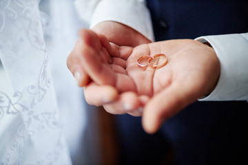 groom holds wedding rings in his hands