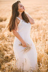 Fototapeta na wymiar beautiful girl with brunette hair on a wheat field background. warm summer time. 