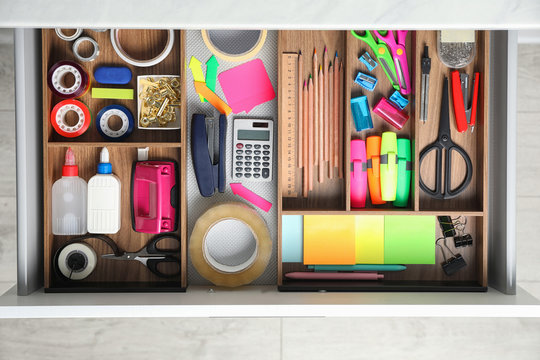 Different stationery in open desk drawer, top view