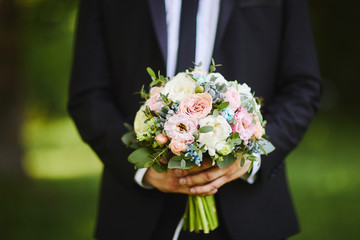 the groom holds a bouquet of flowers