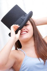 Attractive laughing young woman wearing a top hat