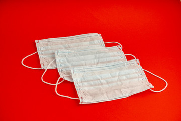 Set of three White medical masks. Medical protective masks over red background. Healthcare and...