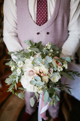 the groom holds a bouquet of flowers