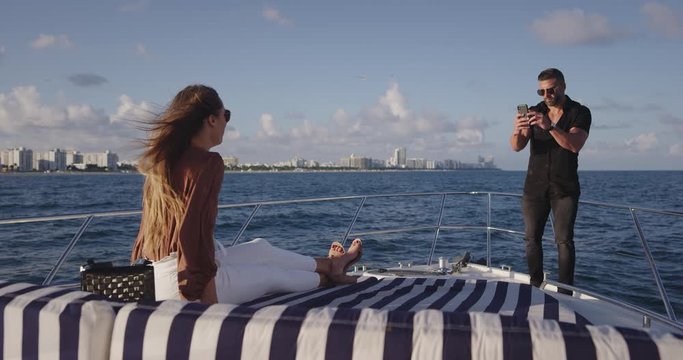 Man taking photo of girlfriend on boat in ocean