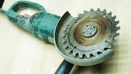 Close-up of a saw on a table. A round iron saw with sharp teeth for working with wood at home against a light wood background. A working old, dirty electric tool