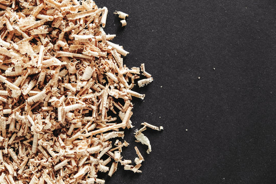 Wood Shavings On Black Background. Background Of Fresh Wood Shavings. Copy, Empty Space For Text