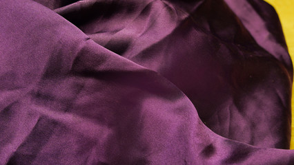 Abstraction, background of silk purple matte fabric. Dark drapery fabric. Satin texture. Beautiful fashionable silk color of fabric.