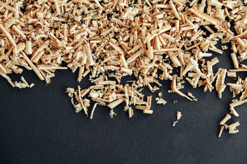 Wood shavings on black background. Background of fresh wood shavings. Copy, empty space for text