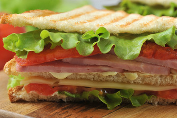 Sandwich close-up.  The delicious sandwich filling consists of green salad, ham, cheese, sauce and slices of tomato.  Macro shot.