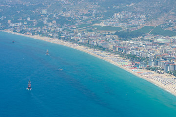 Fototapeta na wymiar Alanya. Turkey. The city beach in Alanya. The coastline is receding into the distance. The view from the bird's eye view. Alanya - a popular holiday destination for European tourists.