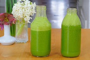 Glass bottles filled with fresh kale and ginger green smoothie