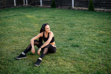 Young sporty woman sits on the lawn