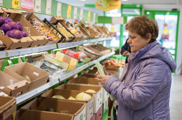 Obraz premium Russia, Ryazan - March 27, 2020: a female customer buys products in a supermarket and puts them in a shopping trolley.