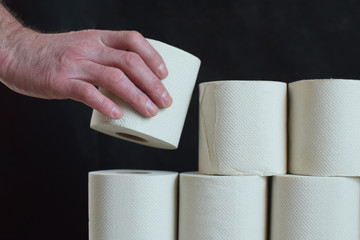 A man holds a roll of toilet paper. Hand with toilet paper close-up. Concept: diarrhea, hygiene.