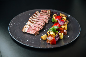  Beef tagliata, meat, with potatoes and tomatoes and herbs, side view, horizontal