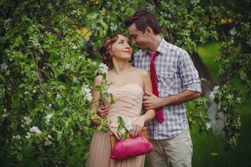 A guy and a girl in 60s clothes stand hugging a blooming tree in the Park