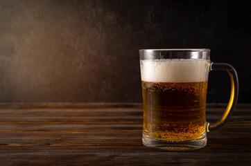 light beer, beer mug with foam on a dark wooden background, alcoholic beverage