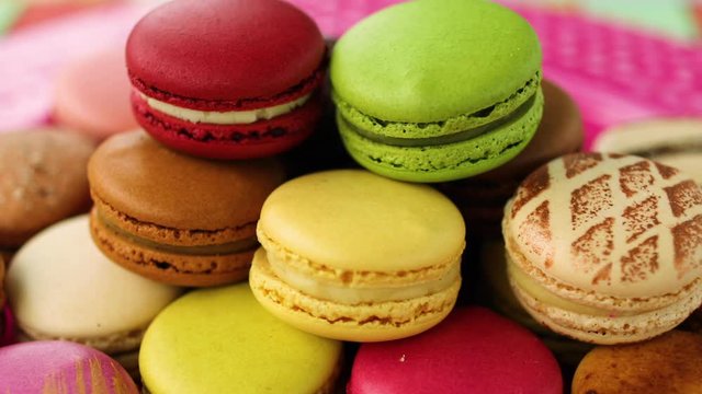 Macarons tower on dessert plate at home. Cute retro vintage pink plate on checkered tablecloth easter table decoration home kitchen. Assortment of pastel colored macaron of different flavors.