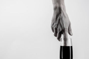 The hand dips its index finger into a glass of black liquid. Minimalism. Black and white photo. Copy space