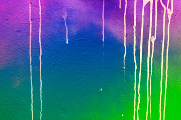 Plastered wall background with colorful drips, flows, streaks of paint and paint sprays