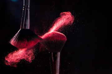 Colorful explosion on makeup brushes on a black background