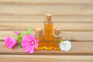 Fototapeta na wymiar mallow essential oil in beautiful bottle on wooden background