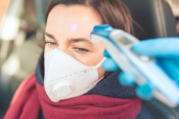 Temperature check point - the woman behind the wheel of the car in an anti-virus mask is subjected...
