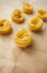 Italian wheat pasta tagliatelle on a craft paper. Top view