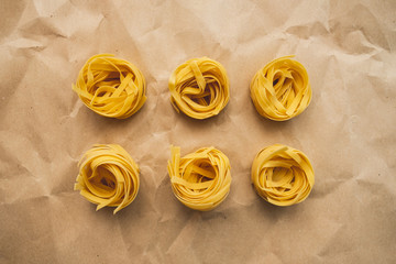 Italian wheat pasta tagliatelle on a craft paper. Top view