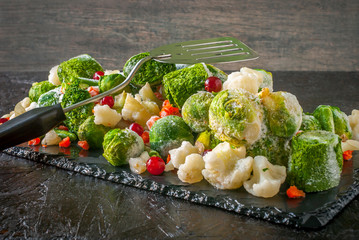 Frozen vegetables and fruits on a black slate blackboard.