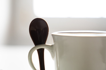 Ceramic spoon from a coffee cup with the light from a window in the background