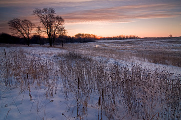 A winter sunrise over a tranquil, snow-covered Midwest prairie.
