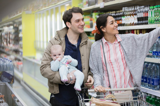 Couple with baby shopping in supermarket