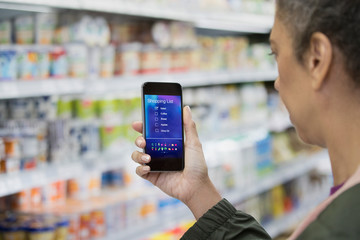 Woman with digital shopping list on smart phone in supermarket