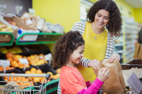 Mother and daughter shopping for produce in supermarket