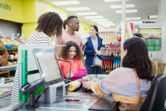 Cashier helping customers at supermarket checkout