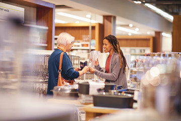 Female worker helping senior woman shopping in home goods store