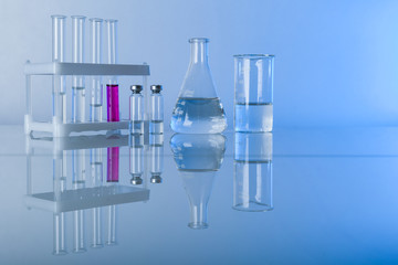 conceptual background with chemical flasks. blue backdrop with lab glassware with copy space....