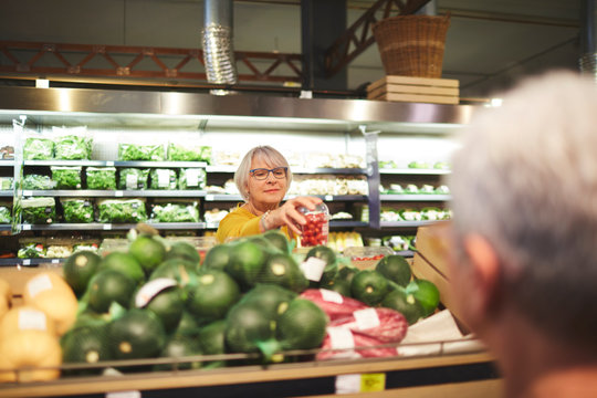 Senior woman shopping for tomatoes in supermarket produce section