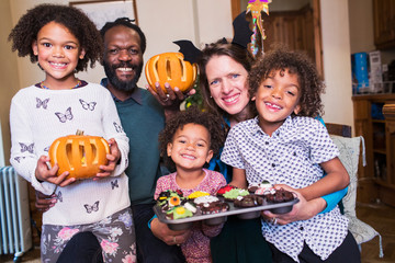 Portrait happy family with carved pumpkins and Halloween cupcakes