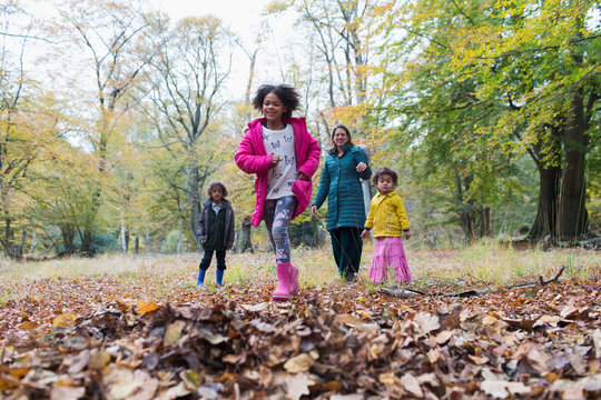 Happy family running and playing in autumn woods
