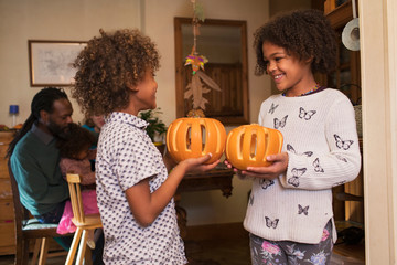 Happy brother and sister holding carved pumpkins
