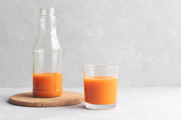 Glass bottle with carrot juice and a glass of juice stand next to a gray background. A healthy diet. Fresh Juice. Copy space