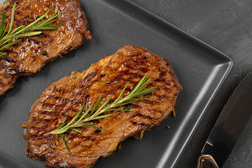 Grilled Beef steaks served with rosemary on  metal tray, close up