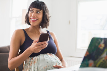 Happy pregnant woman using smart phone