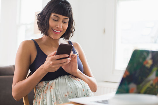 Happy pregnant woman using smart phone