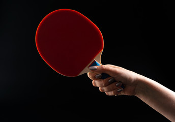 Red ping pong racket on dark background. Sports equipment