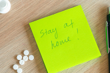 Stay at home written on an adhesive note and medical pills. Coronavirus quarantine concept