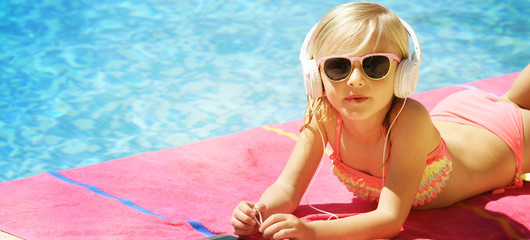 Children blond girl in swimming pool. Summer vacations.